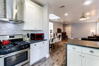 a kitchen with a stove top oven next to a living room at Stylish Modern Lake Balboa Retreat 3 Bedroom House in Van Nuys