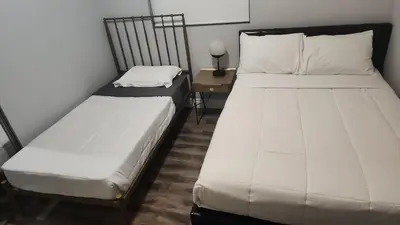 two beds in a small room with a night stand at Stylish Modern Lake Balboa Retreat 3 Bedroom House in Van Nuys