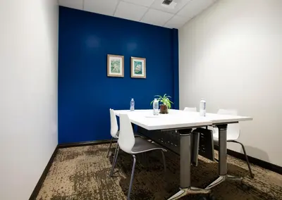 a conference room with a blue wall and a table and chairs at Redac Gateway Hotel Torrance in Torrance