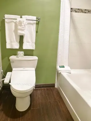 a bathroom with a white toilet and a bath tub at Redac Gateway Hotel Torrance in Torrance