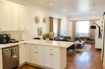 a kitchen with white cabinets and a living room at Mid Century Modern - Walk to Dodger Stadium, DTLA in Los Angeles