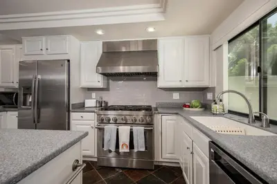 a kitchen with white cabinets and a stainless steel stove at Peaceful Private Retreat In The Heart Of Town in Redlands