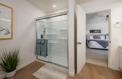 a glass shower door in a bedroom with a bed at Peaceful Private Retreat In The Heart Of Town in Redlands