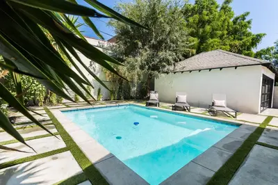 a swimming pool with two chairs in front of a house at Modern Bungalow with a Pool in Larchmont Village in Los Angeles