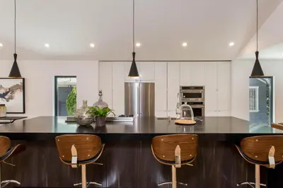a kitchen with a large island with wooden bar stools at Modern Bungalow with a Pool in Larchmont Village in Los Angeles
