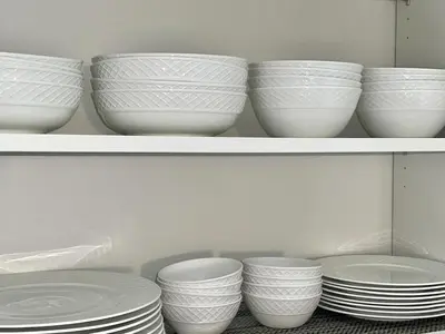 a row of white bowls and plates on a shelf at Huge Family Home Near Disneyland & SoCal Beaches in Midway City