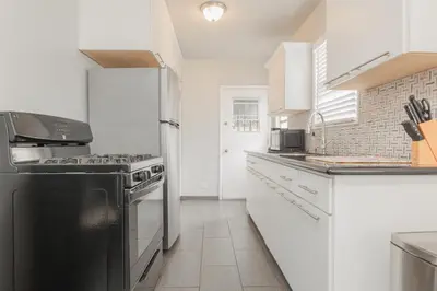 a kitchen with a black stove and white cabinets at Cool and Cozy Pad Close to Everything in Los Angeles