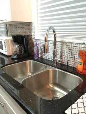 a stainless steel kitchen sink in a black counter top at Cool and Cozy Pad Close to Everything in Los Angeles