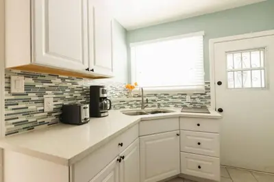 a kitchen with white cabinets and a sink and a window at Inviting Home in Historic Leimert Park in Los Angeles