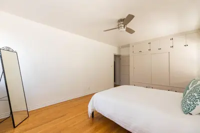 a bedroom with a white bed and a ceiling fan at Inviting Home in Historic Leimert Park in Los Angeles