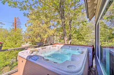 a hot tub on a balcony with a tree at Chic Lake House with Furnished Deck and Hot Tub! in Lake Arrowhead
