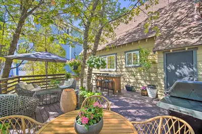a patio with a table and chairs and an umbrella at Chic Lake House with Furnished Deck and Hot Tub! in Lake Arrowhead