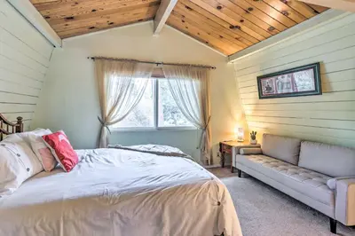 a bedroom with a bed and a couch and a window at Château Forêt in Big Bear with Hiking Trail Access in Big Bear City
