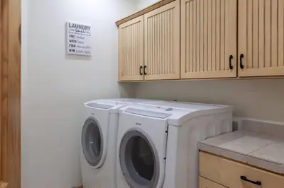 a washer and dryer in a kitchen with wooden cabinets at Hillside Hideaway - game rm - master spa - Luxury in Lake Arrowhead