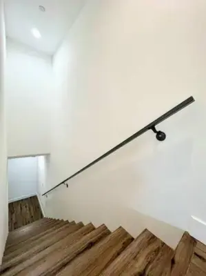 a metal rail on a white wall with wooden stairs at 4BR Townhouse in KoreaTown in Los Angeles