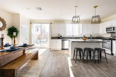 a kitchen with white cabinets and a island with bar stools at Spacious Modern Home in Sierra Lakes Fontana in Fontana