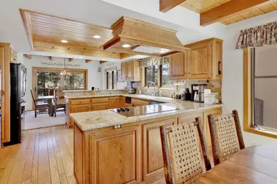 a large kitchen with wooden cabinets and a dining room at Cove Lakefront Chalet #2098 by Big Bear Vacations in Big Bear Lake