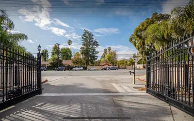 an open gate to a parking lot with palm trees at LA Dream Gem - Beautiful Home with Spa in Los Angeles