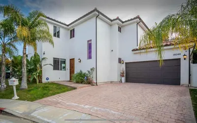 a white house with a garage and palm trees at LA Dream Gem - Beautiful Home with Spa in Los Angeles