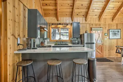 a kitchen with a counter and stools in a cabin at Modern Cabin with Hot Tub Ski and Hike Big Bear! in Big Bear Lake