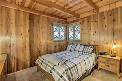 a bedroom with wooden walls and a bed and a window at Modern Cabin with Hot Tub Ski and Hike Big Bear! in Big Bear Lake