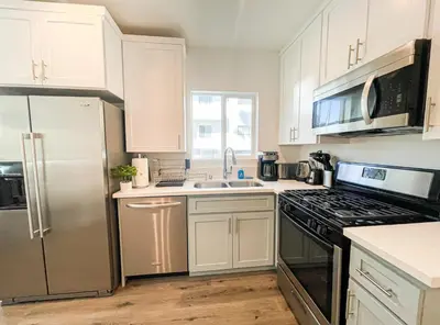 a kitchen with white cabinets and a stainless steel refrigerator at Cozy Habitat in Los Angeles