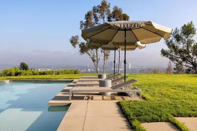 a pool with a table and an umbrella and benches at Vue Modern in Los Angeles