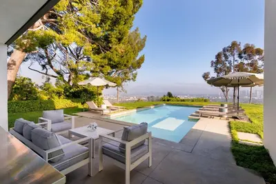 a backyard with a pool and chairs and an umbrella at Vue Modern in Los Angeles