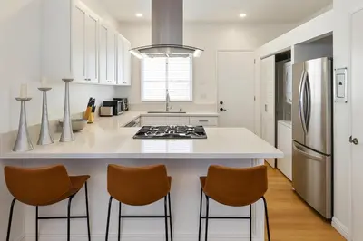 a kitchen with a large white island with three bar stools at Exclusive 2BD 3BA with Balcony in Los Angeles