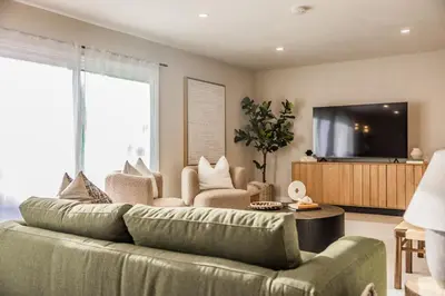 a living room with a green couch and a tv at @ Marbella Lane - Vibrant & Chic Designer Home in Fullerton