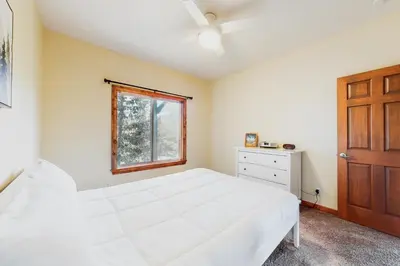 a bedroom with a large white bed and a window at Deer Mountain in Lake Arrowhead