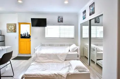 a bedroom with a white bed and a yellow door at King Garden Suite - 10 mins to Beach and LAX in Gardena