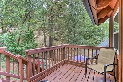 a wooden deck with a chair and a window at Lovely Lake Arrowhead Cabin with Furnished Deck in Lake Arrowhead
