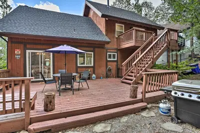 a large wooden deck with a table and an umbrella at Lovely Lake Arrowhead Cabin with Furnished Deck in Lake Arrowhead