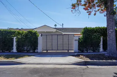 a house with a gate in front of a driveway at New 5 bed w/hot tub close to Universal sleeps 12 in Los Angeles