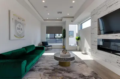 a living room with a green couch and a tv at Modern 5 Bedroom Masterpiece With Rooftop Deck in Los Angeles