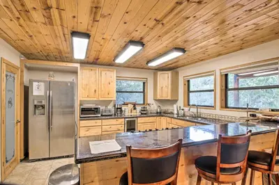 a kitchen with a stainless steel refrigerator and wooden ceilings at Spacious Pine Mountain Club Cabin with Fire Pit in Pine Mountain Club
