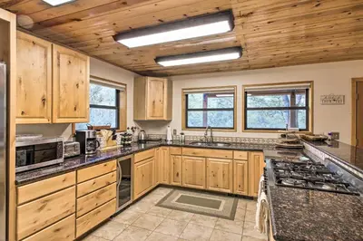 a large kitchen with wooden cabinets and granite counter tops at Spacious Pine Mountain Club Cabin with Fire Pit in Pine Mountain Club