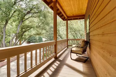 a porch of a cabin with a chair and trees at Spacious Pine Mountain Club Cabin with Fire Pit in Pine Mountain Club
