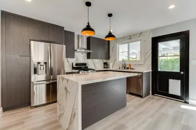 a kitchen with stainless steel appliances and wooden floors at 4 Bedroom West Hills Charmer with Pool in West Hills