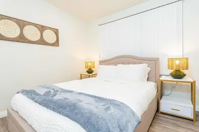 a white bedroom with a bed and two night stands at Newly Remodeled 2B1B House on Historic Route 66 in Glendora