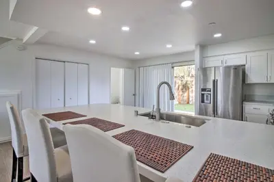 a kitchen with a large kitchen island with chairs and a sink at Central Bakersfield Townhome with Private Patio in Bakersfield