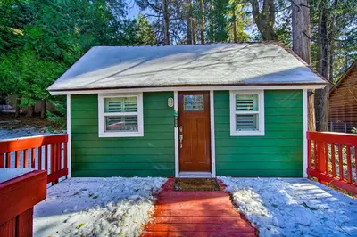 a green tiny house with a snow covered porch at Running Springs Cabin with Deck and Forest Views in Running Springs
