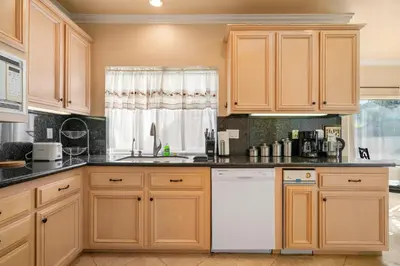 a kitchen with wooden cabinets and a white dishwasher at @ Marbella Lane - Captivating Home in Rowland Hts in Rowland Heights