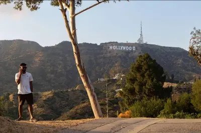 a man standing on the side of a road talking on a cell phone at Hollywood Hideaway in Los Angeles