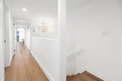 a white hallway with white walls and a chandelier at Malibu Beachfront Home with Rock Spa Ocean Views & Huge Deck in Malibu