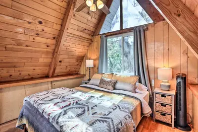 a bedroom with a bed in a wooden cabin at Cozy A-Frame with Hot Tub Near Arrowbear Lake! in Running Springs