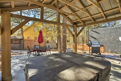 a covered patio with a table and chairs and a grill at Cozy A-Frame with Hot Tub Near Arrowbear Lake! in Running Springs