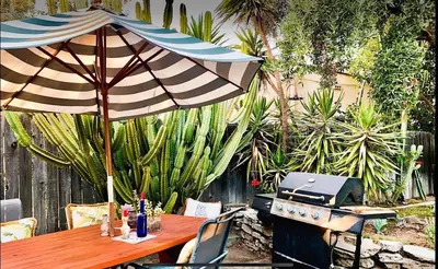a wooden table with an umbrella and a grill at Romantic cottage with amazing garden in Glendale