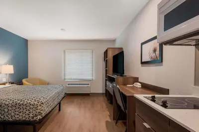a bedroom with a bed and a sink in a room at WoodSpring Suites Bellflower - Los Angeles in Bellflower